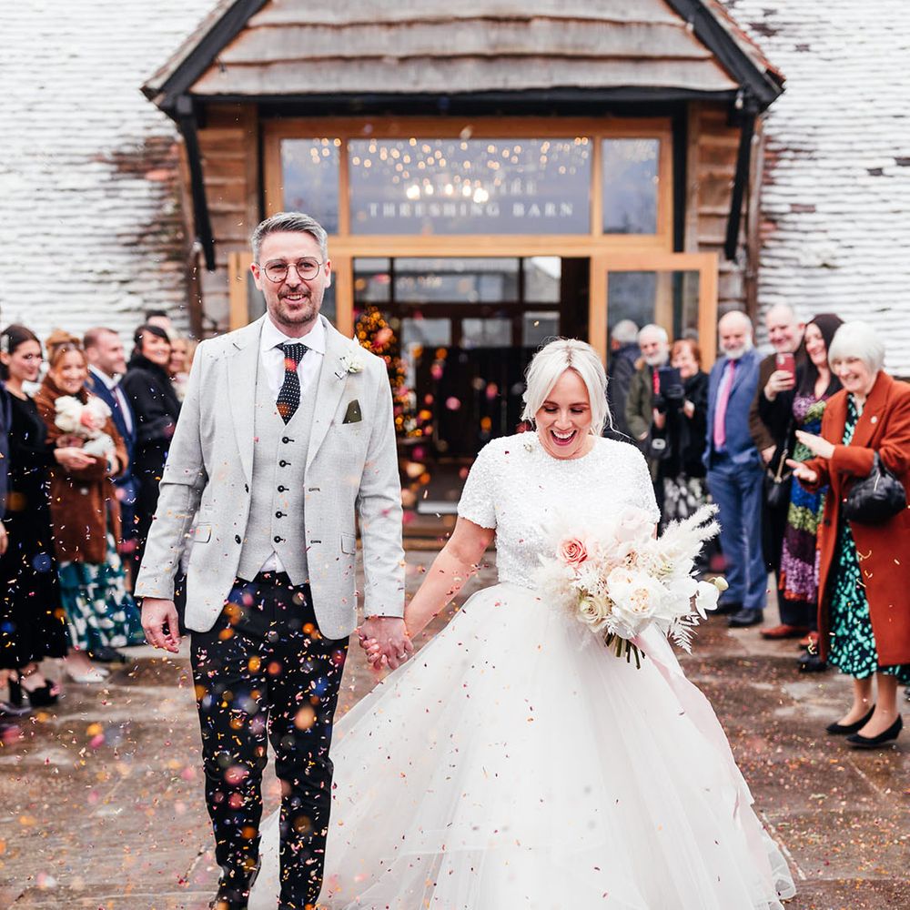 Bride in tulle bridal separates walking with the groom in a light grey suit jacket and waistcoat and spotted tie with black trousers 