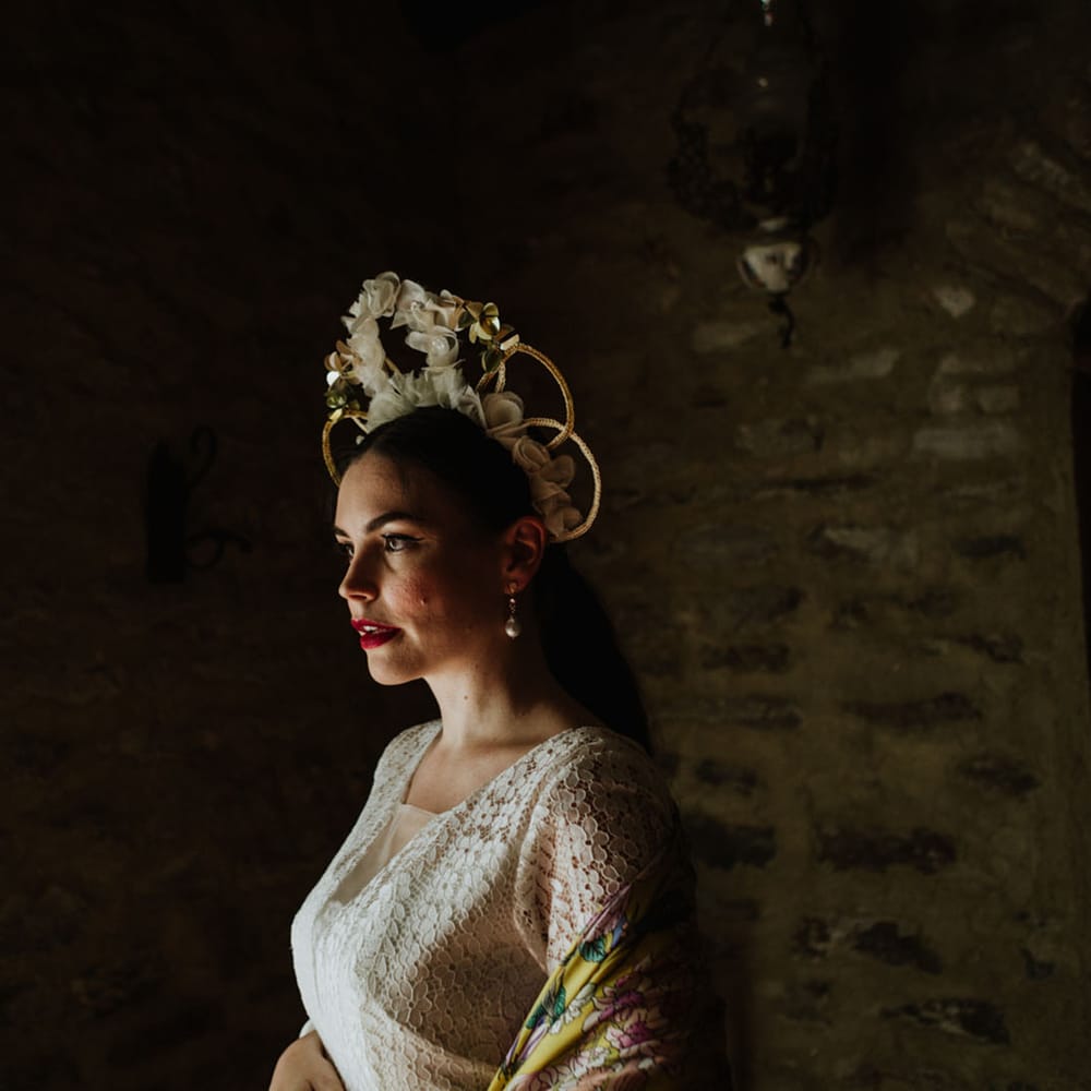 Bride inn white floral bridal crown and bohemian lace dress with a colourful pashmina, pearl earrings and red lip makeup look
