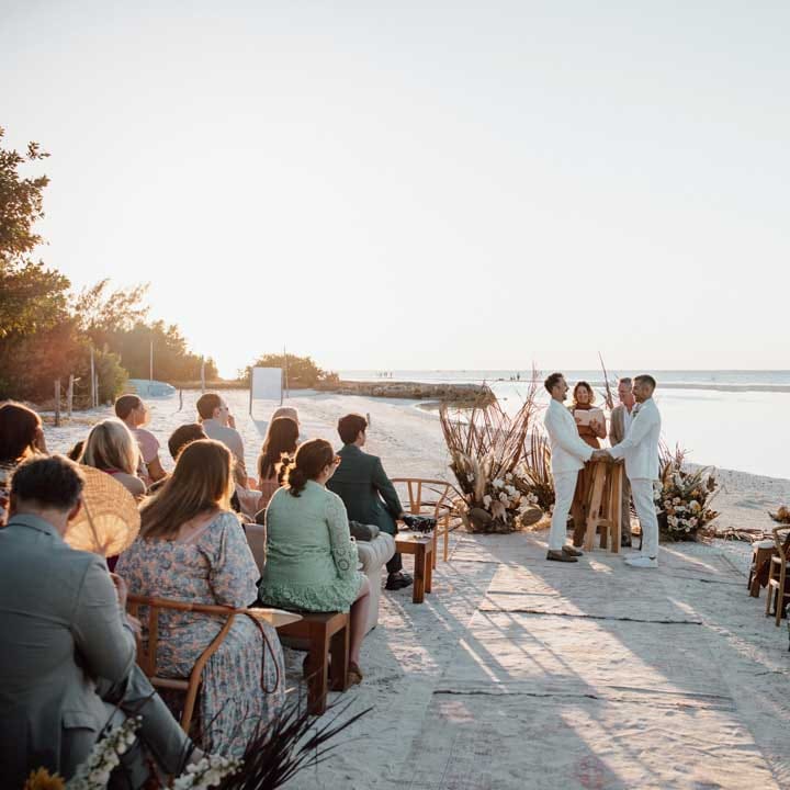 Grooms in complimenting white wedding suits at the alter on white sand beach wedding in Mexico 