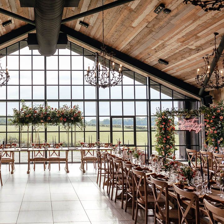 The Barn at Botley Hill wedding venue with colourful flower arrangements, neon signage and table decor with a blue and orange colour scheme
