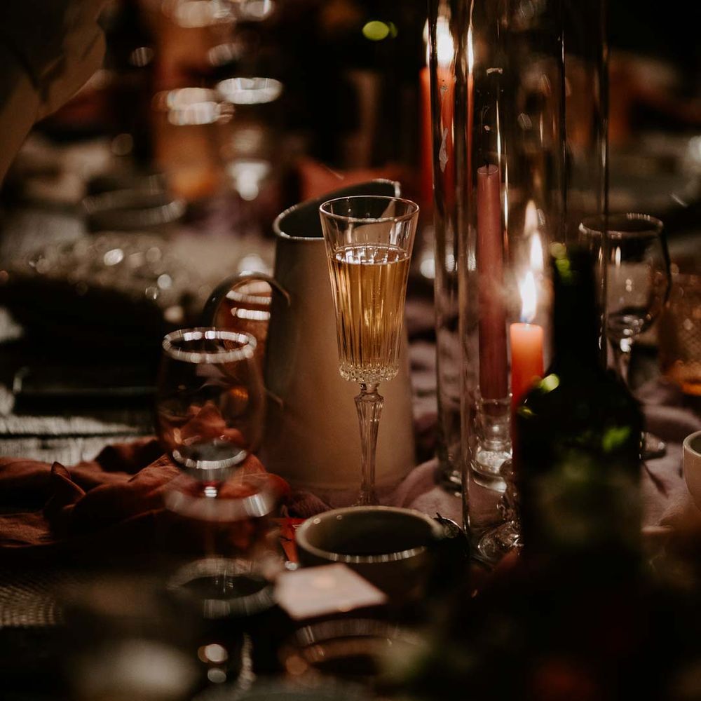 Rustic luxe wedding tablescape with long pink and purple tapered candles, tall candle glass jars, flower and foliage centrepieces and retro wedding signage 