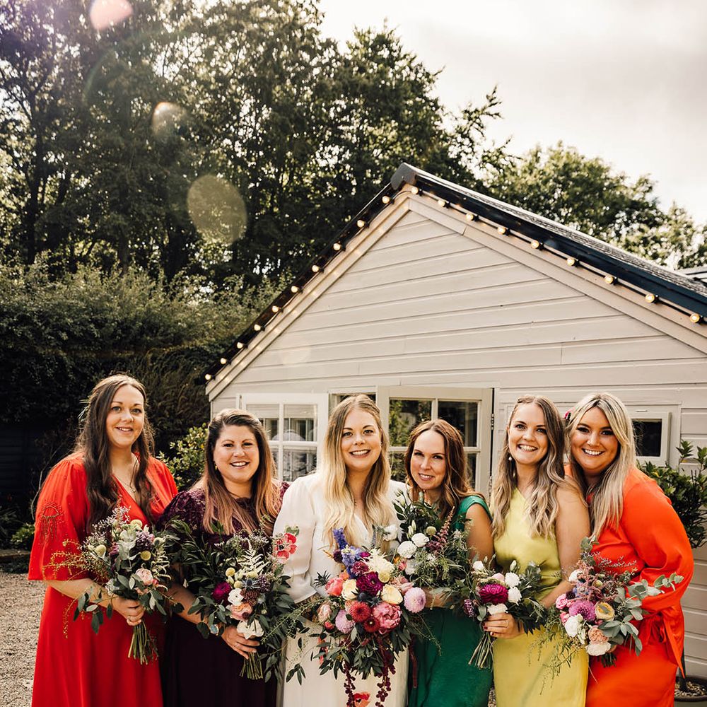 Bridesmaids in colourful bridesmaid dresses in shades of orange, yellow and green for boho wedding 