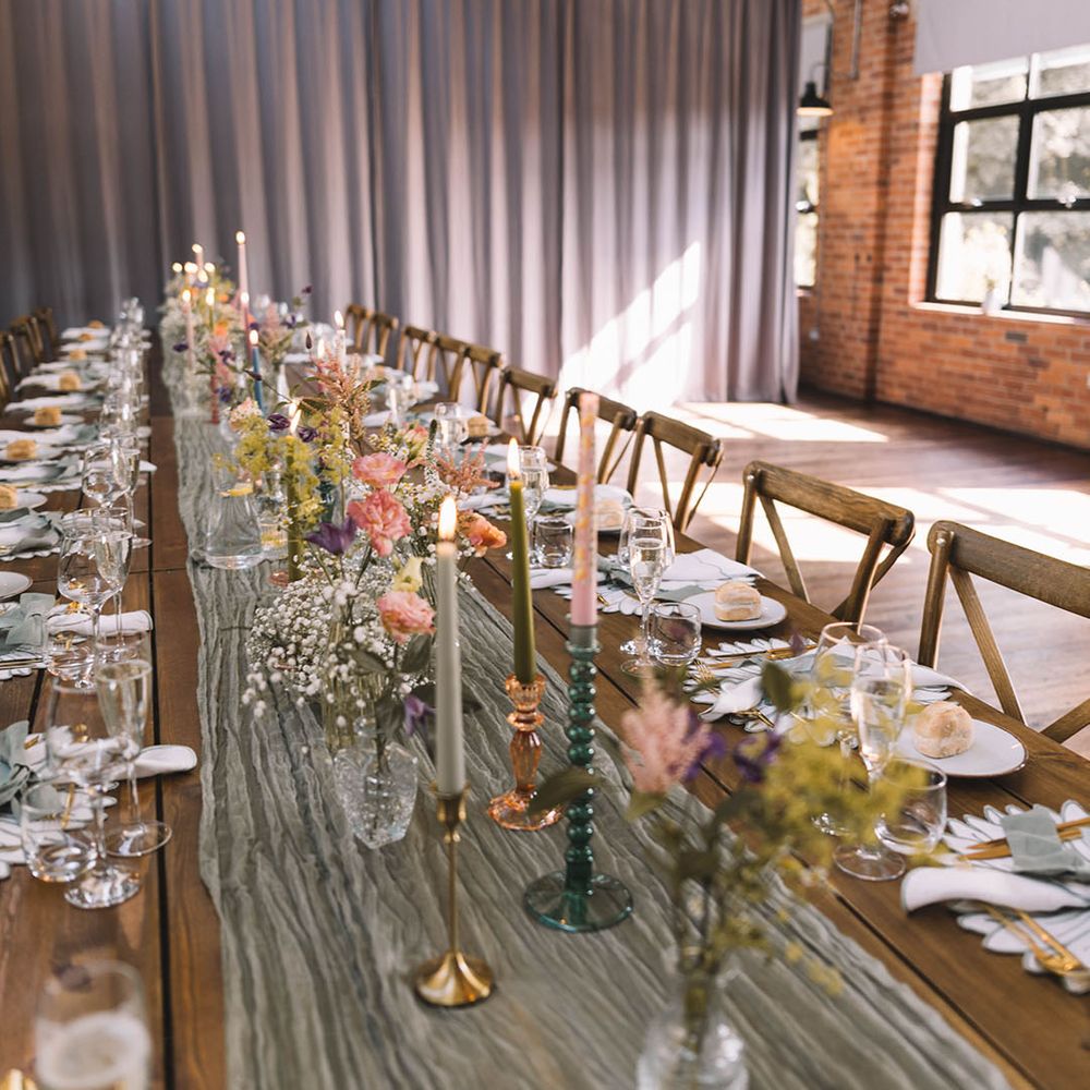 Pastel wedding theme tablescape with sage green table runner, flowers and bud vases 