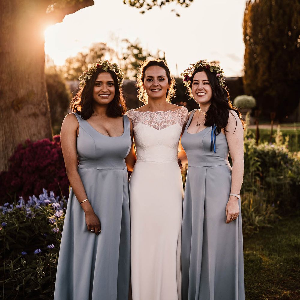 Bride in lace off the shoulder wedding dress with two bridesmaids in satin blue dresses 