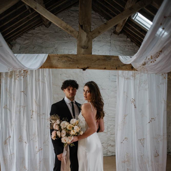 Bride and groom standing at the draped altar by Emmy Shoots 