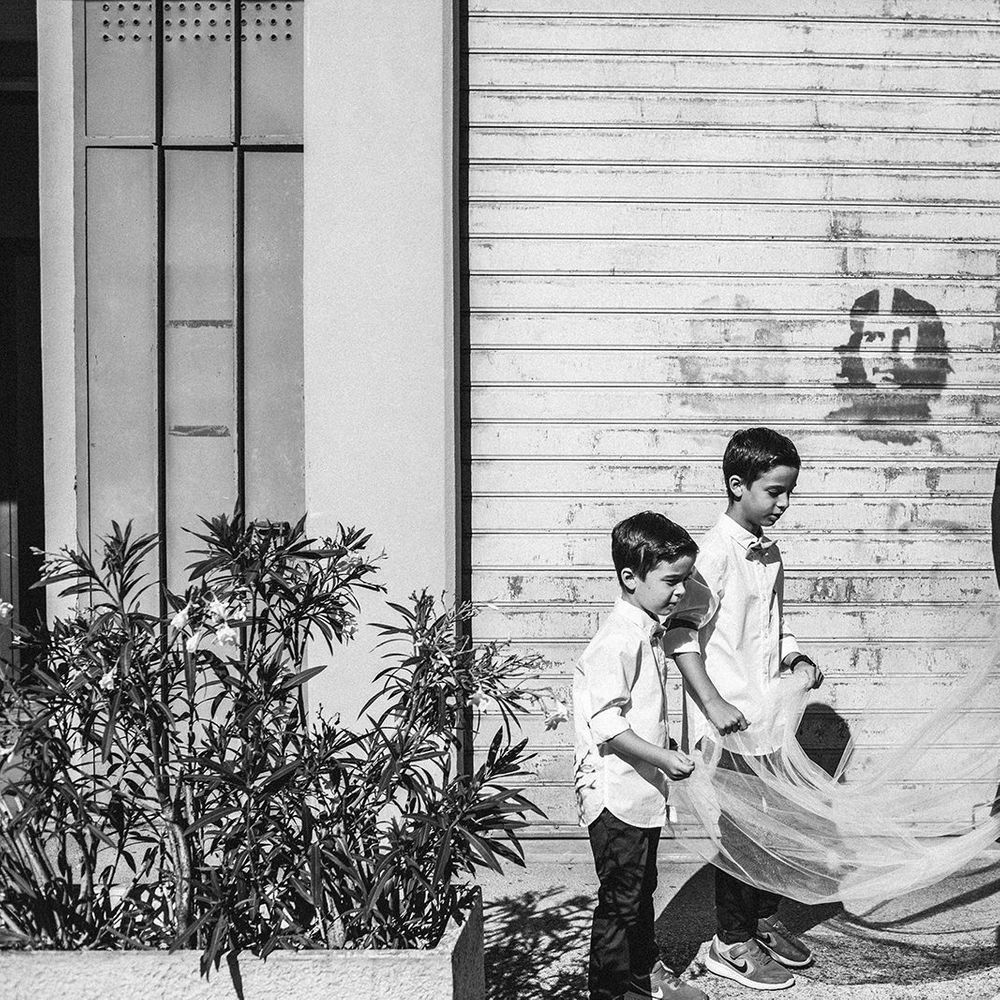 Page boys in trousers, trainers, shirts and bow ties holding the brides wedding train 