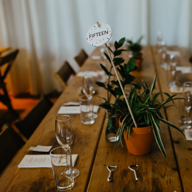 Potted plant table centrepieces with colourful table number sign 