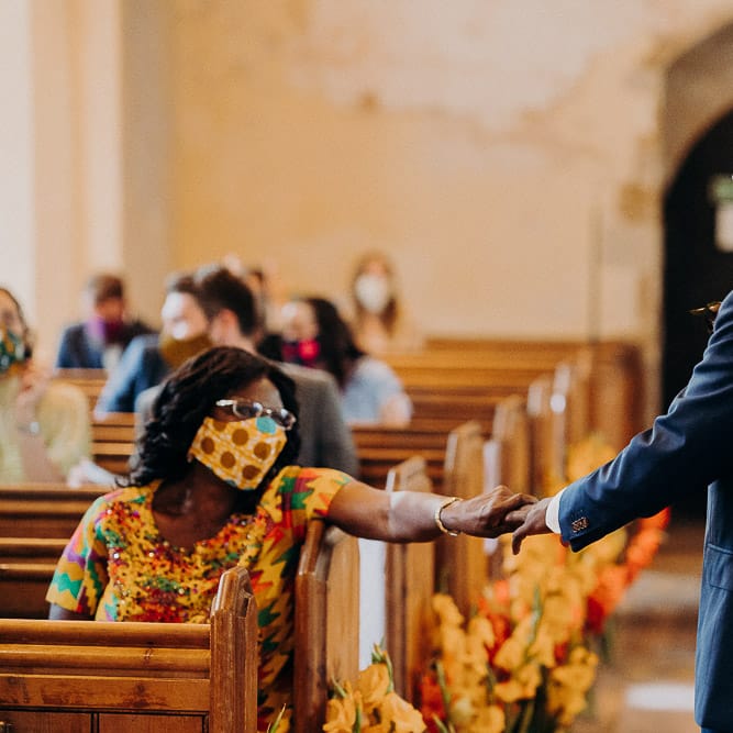Groom in a navy suit at the church wedding altar holding his mums hand 