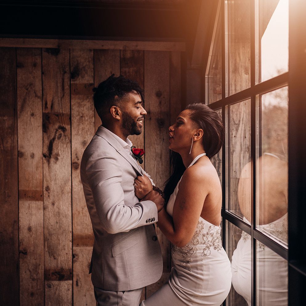 Bride & groom stand in front of window as the light streams through