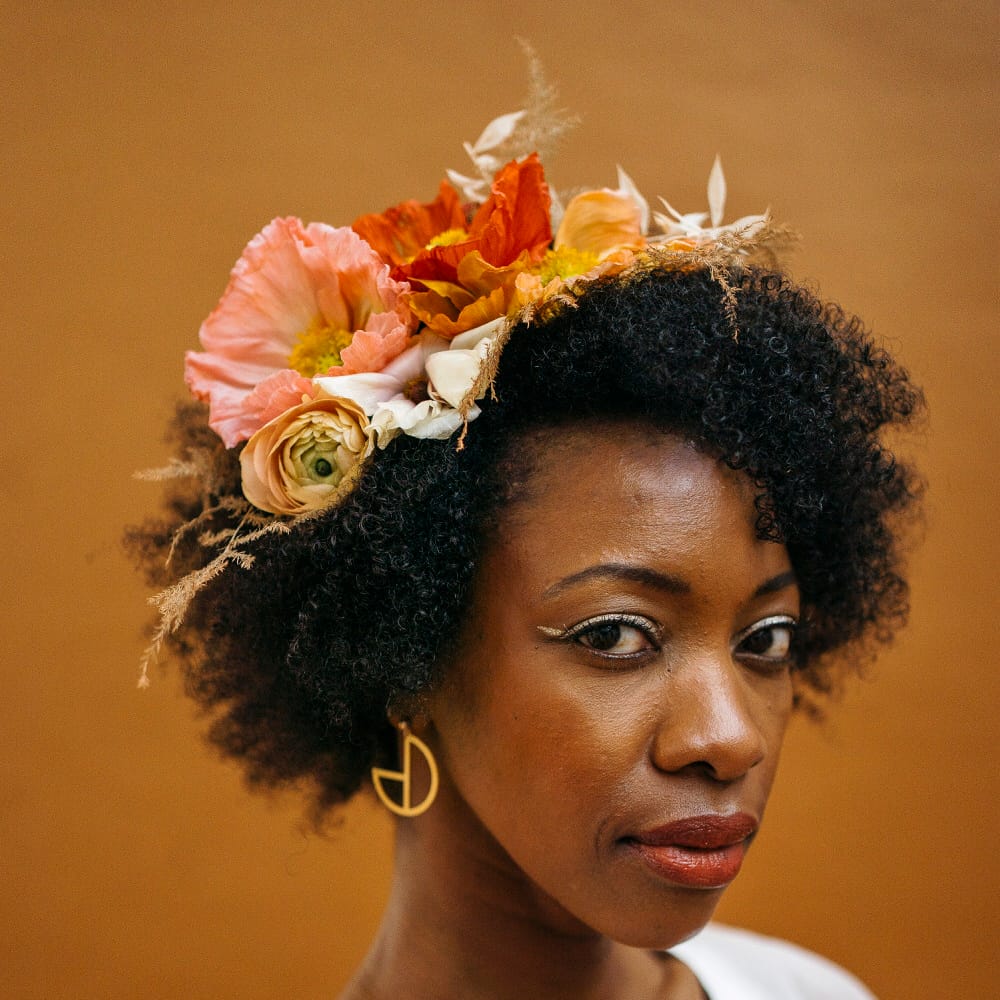 Bride with afro hair wearing a floral headpiece made of fresh flowers including orange poppies