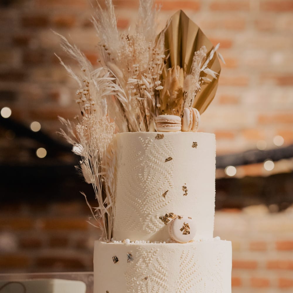 Rustic wedding cake in a wooden tree slice cake stand with dried flower and macaroon decor. 