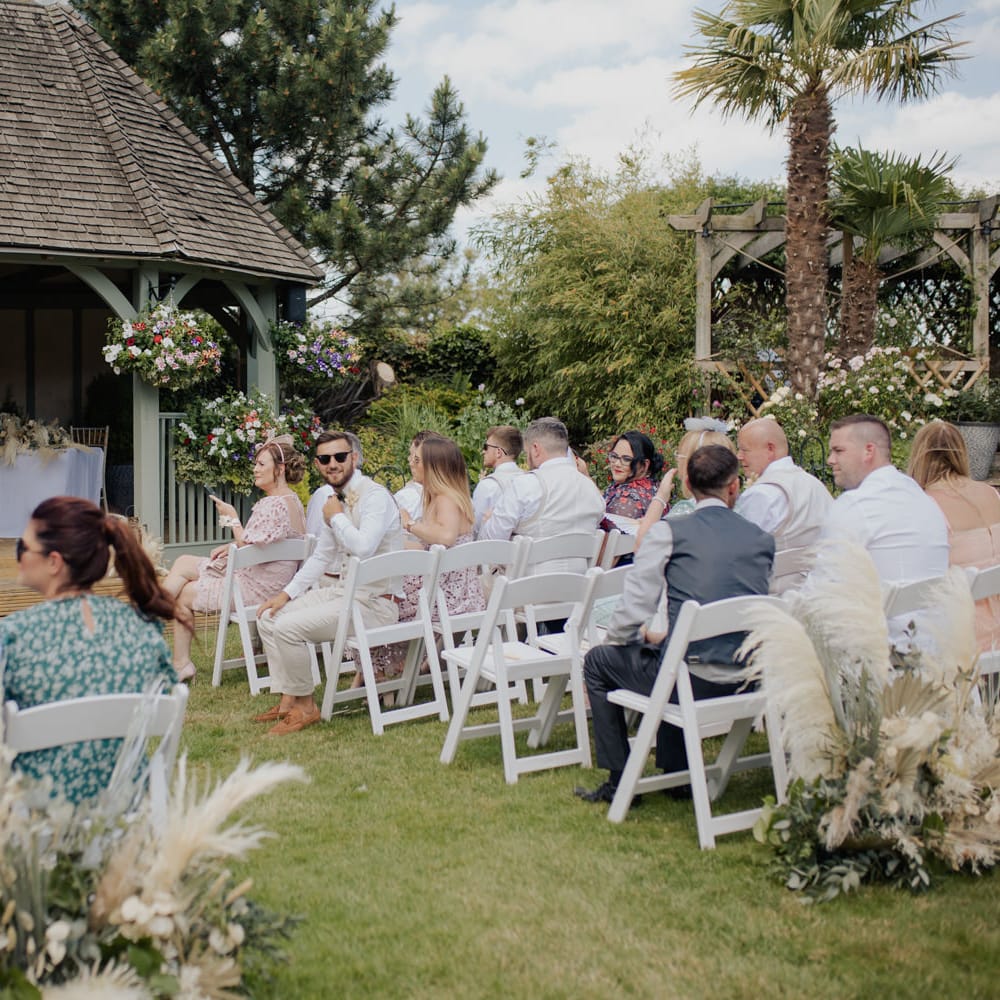 Intimate outdoor wedding ceremony at Cooling Castle Barn with pampas grass floral arrangements 