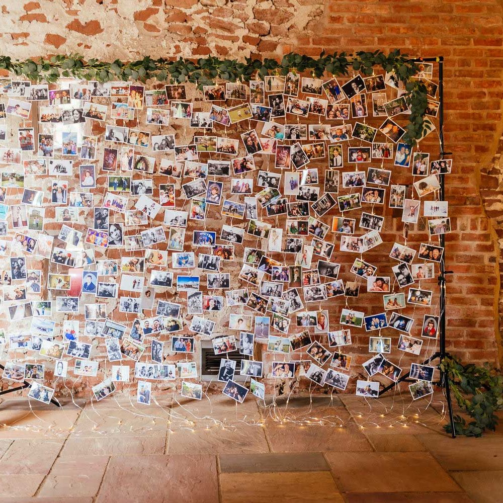 Large fairy light wedding photo wall with leaf garland surround for rustic barn wedding