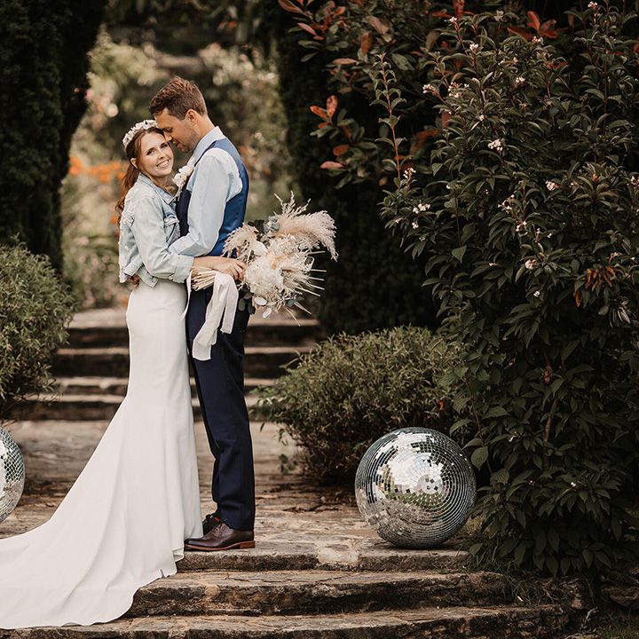 Bride & groom stand on staircase outdoors and kiss on their wedding day
