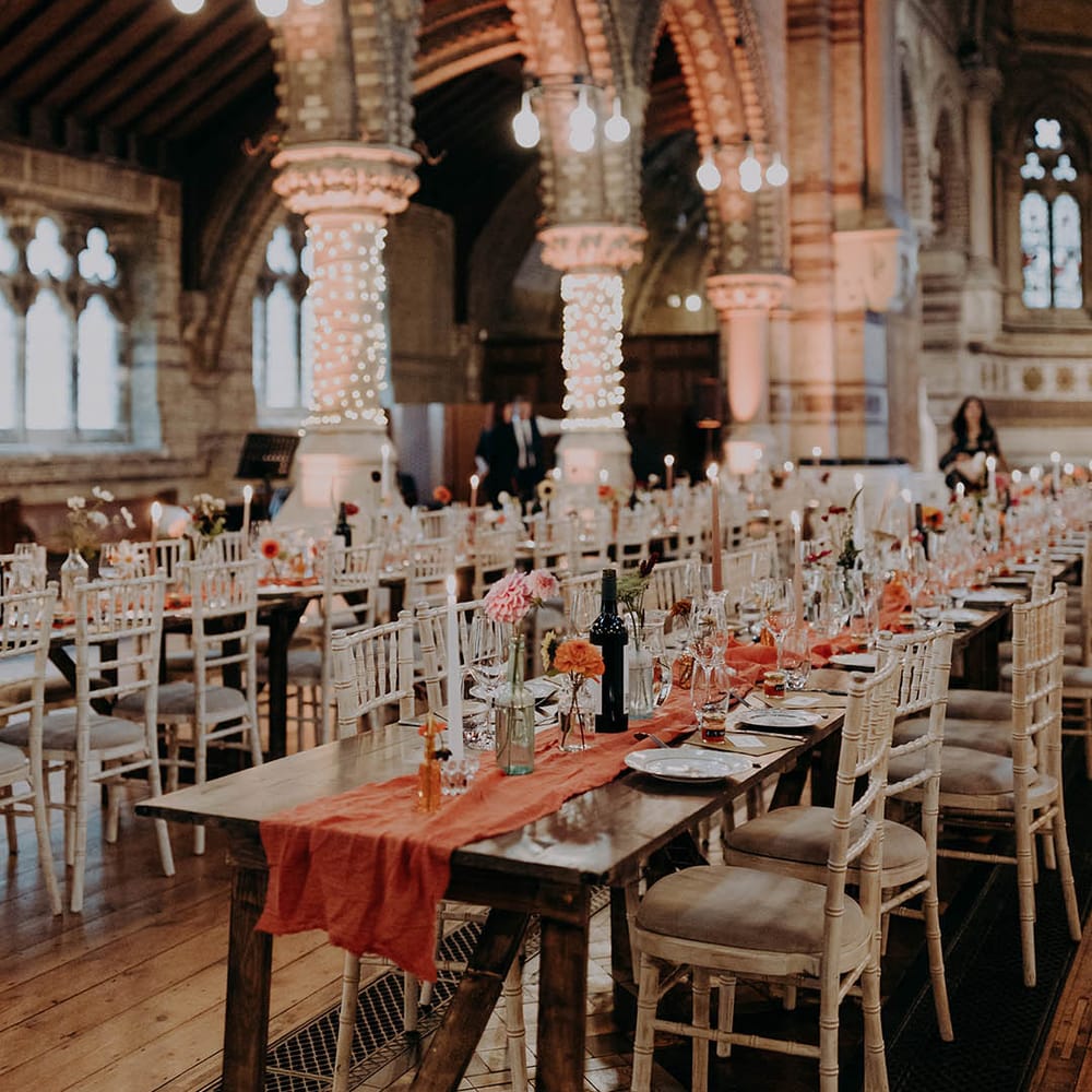 Brightly coloured orange table runner lines wooden rustic tables complete with brightly coloured floral flowers 
