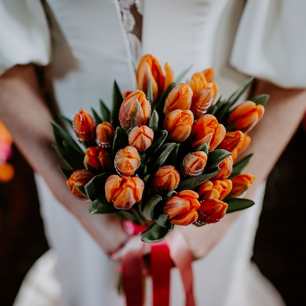 bride holding a orange and red tulip bouquet 