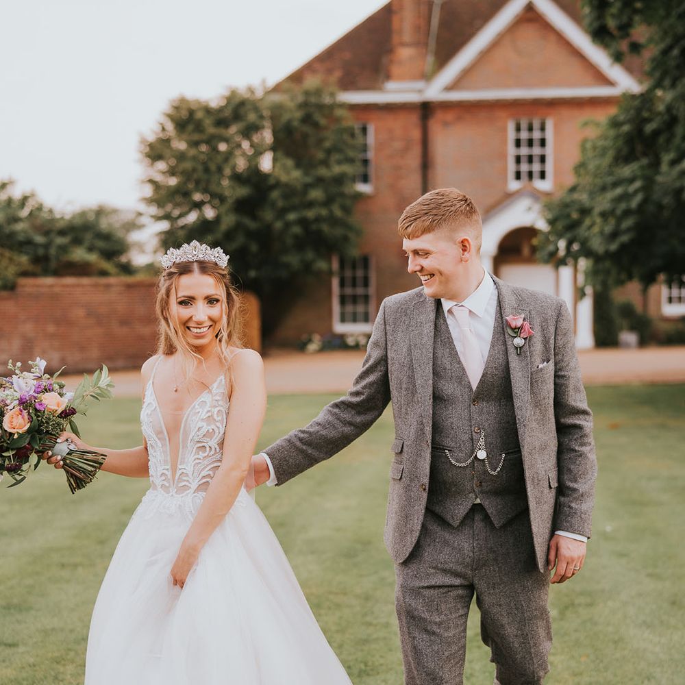 Bride in sparkly plunging deep v neck tulle wedding dress and groom in grey tweed suit with pink tie