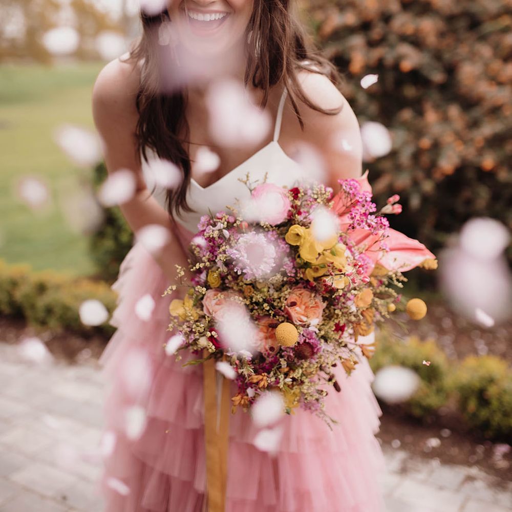 Confetti moment with bride in a pink ruffled wedding skirt and white top bridal separates 
