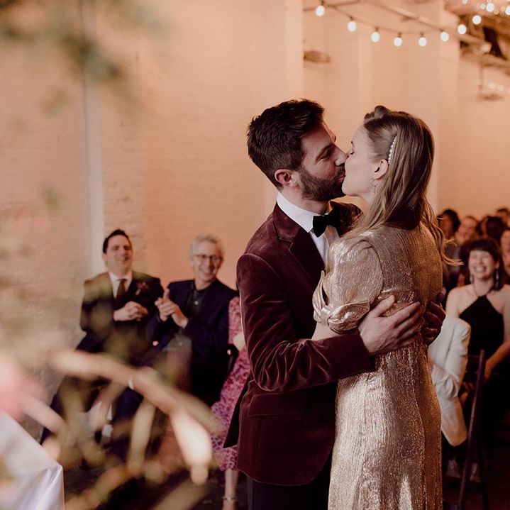 Bride and groom share their first kiss as a married couple in fairy lit industrial wedding venue, 100 Barrington 