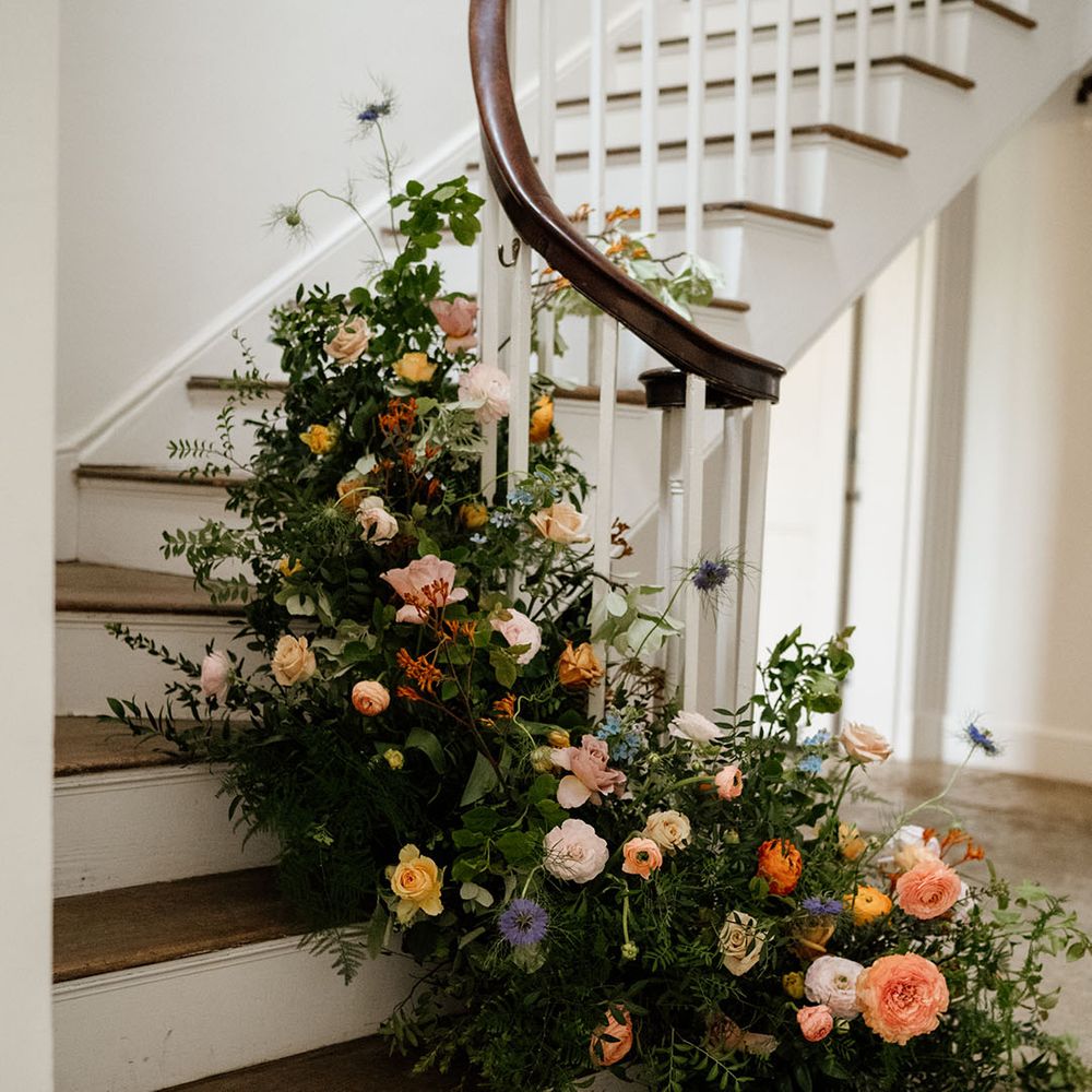 Colourful and bright flowers and greenery on the stairs of Aswarby Rectory wedding venue 