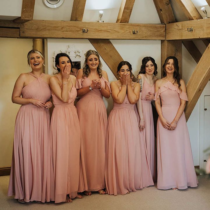 Bridesmaids in pink dresses get their first look at the bride 