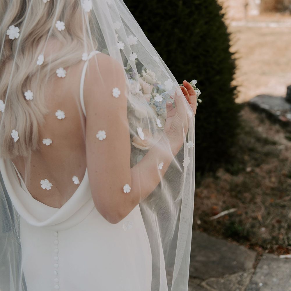 Bride in cowl back wedding dress with buttons wearing a flower applique veil 