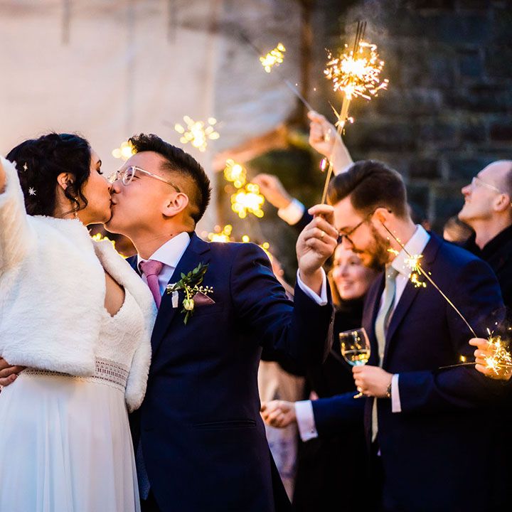 Bride wears faux fur stole and kisses her groom during sparkler exit 
