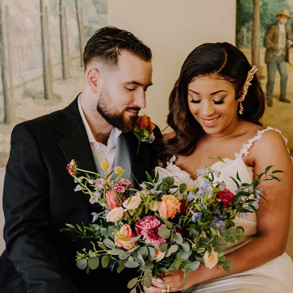 Bride in bow front sleeveless satin wedding dress with large gold bridal hair clip holding large dried flower, eucalyptus, spring florals and garden rose bridal bouquet 