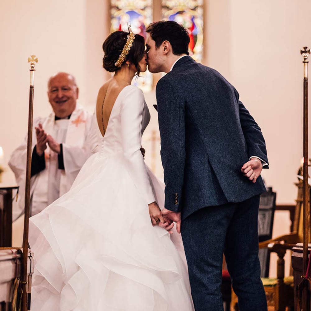 Traditional church wedding in winter with the bride and groom sharing their first kiss as a married couple 