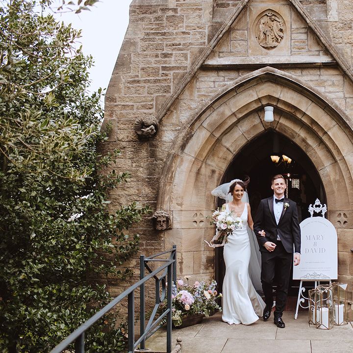 Black tie wedding dress code at church wedding with the groom in black tuxedo and bride in slip gown 