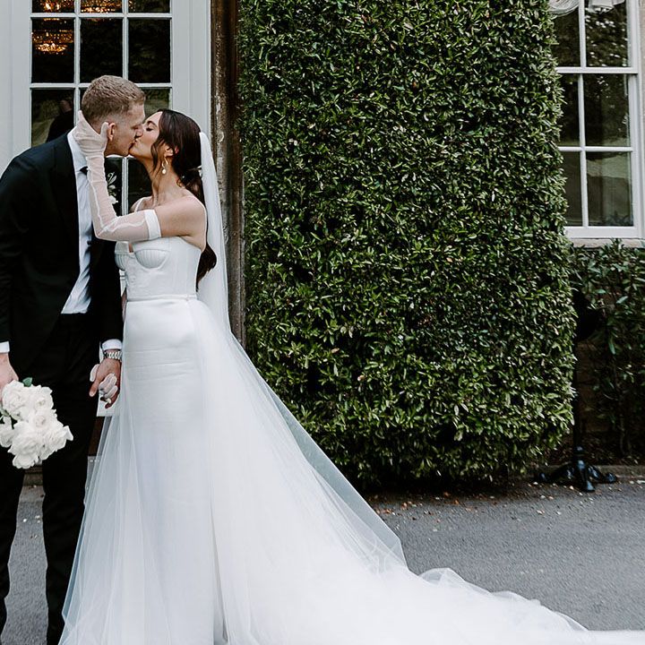 Bride kissing groom in black tuxedo at their classic and elegant luxe wedding 