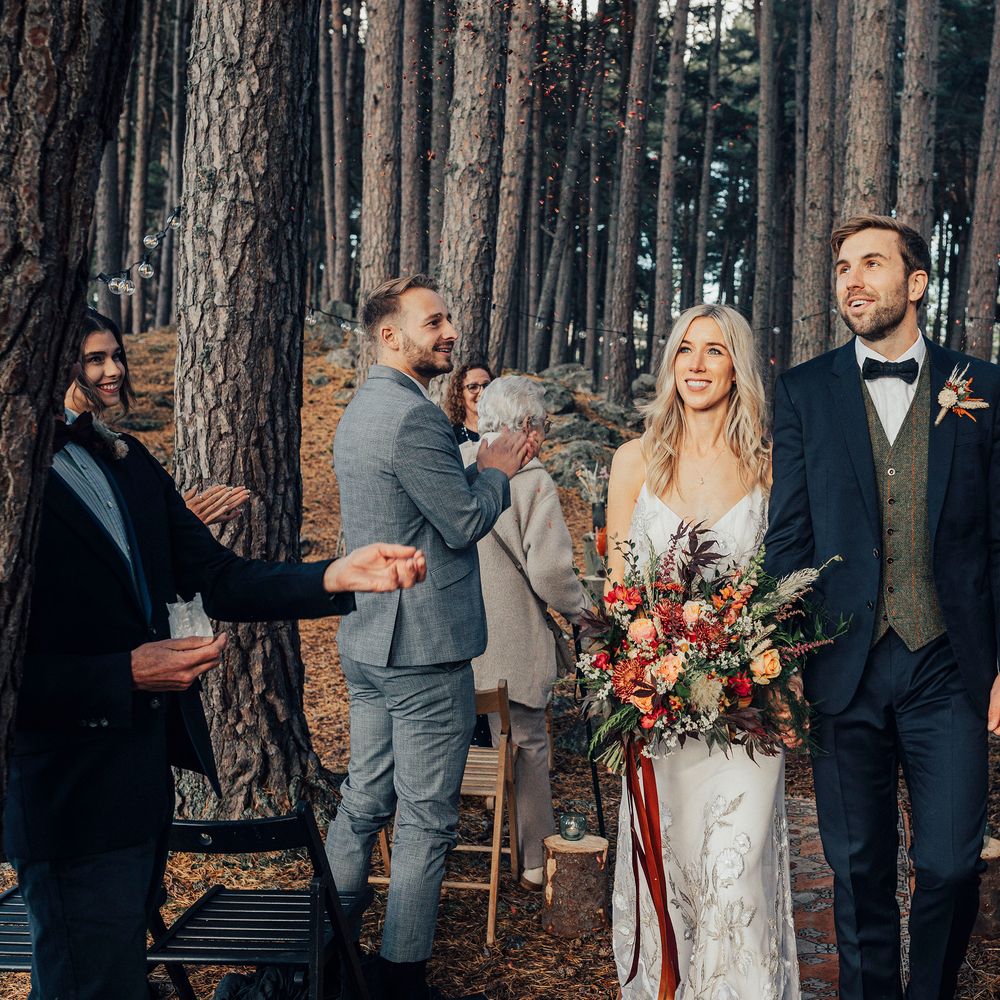 Bride & groom walk through woodland after wedding ceremony