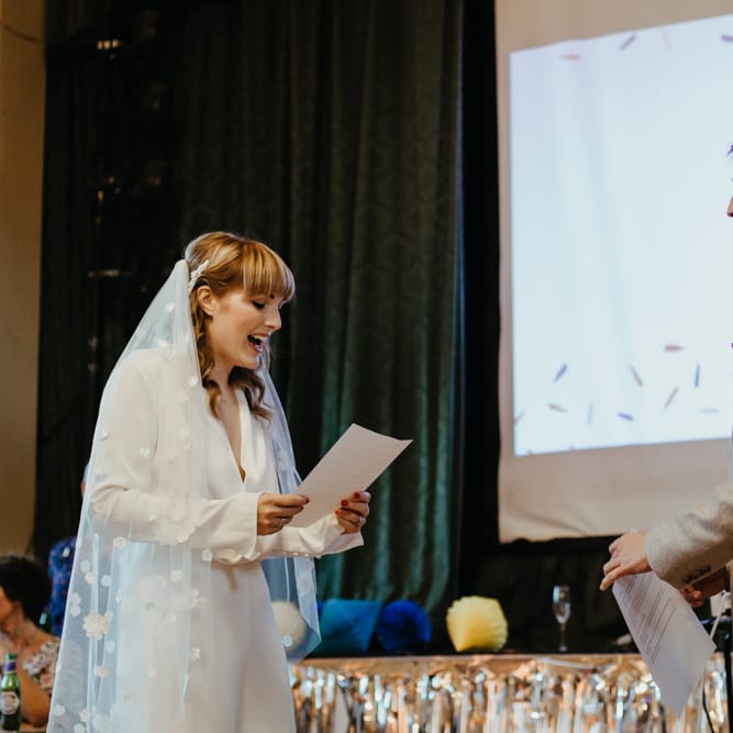 Bride in a jumpsuit with blunt fringe reading her wedding vows at celebrant led ceremony 