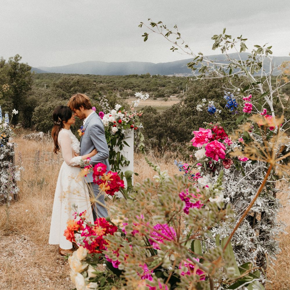 Bride & groom embrace in the mountains surrounded by floral pillars