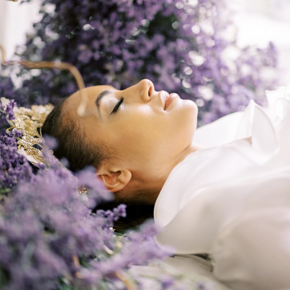 Bride lays within lavender with eyes closed and wearing minimal makeup