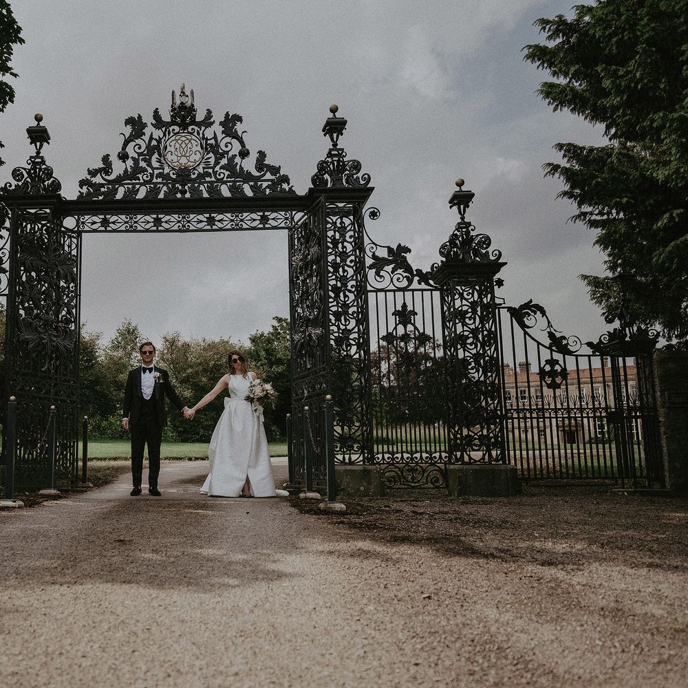 Bride & groom stand in front of black iron gate on the day of their wedding