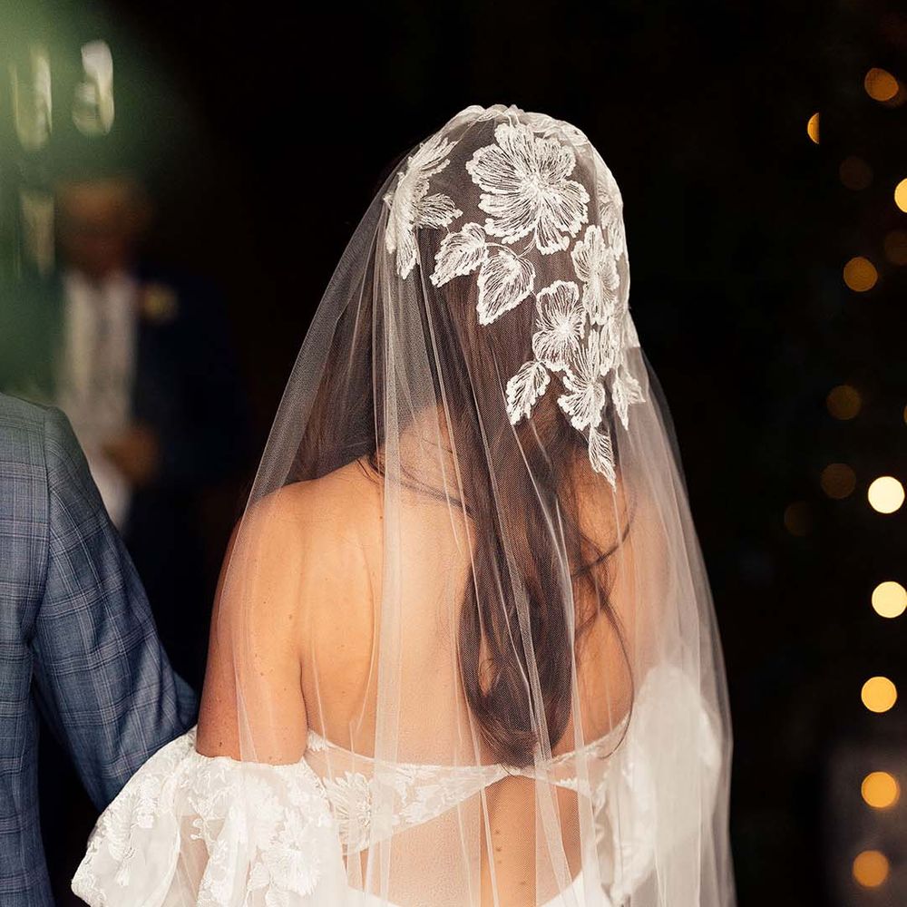 Bride with long dark hair in a cathedral length veil with lace detail on the cap to match the brides puff sleeve wedding dress