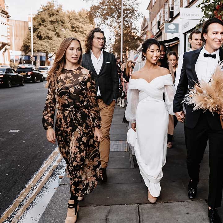 Autumn colour palette wedding as Bride and Groom walk with their wedding guests 