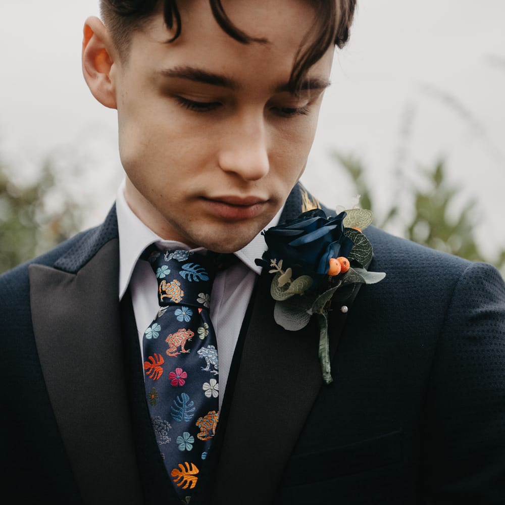Groom in blue blazer with floral tie and blue floral buttonhole for Wellbeing Farm wedding