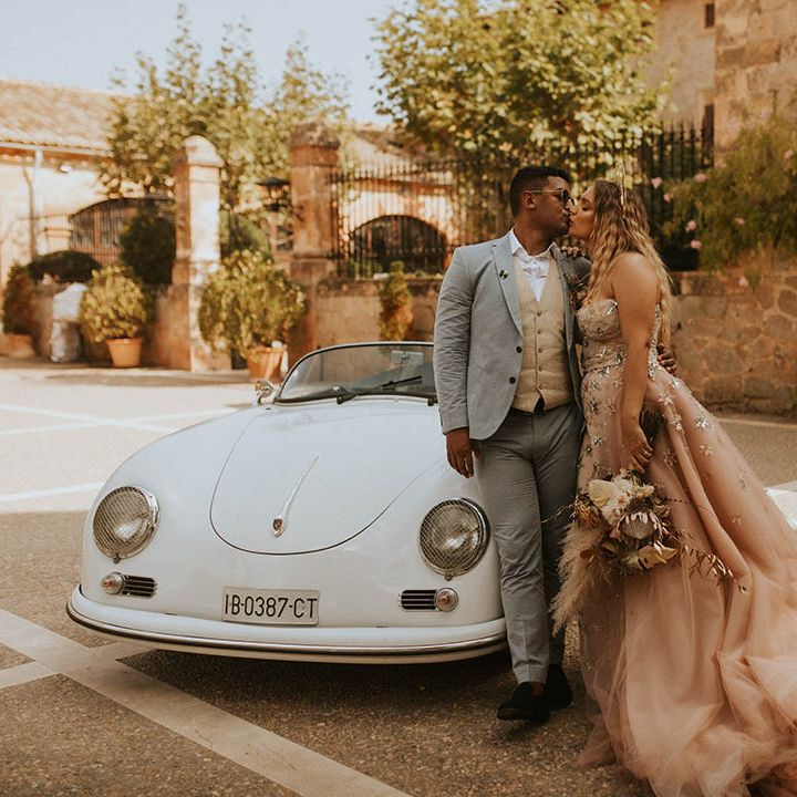 Bride & groom stand beside car on their wedding day