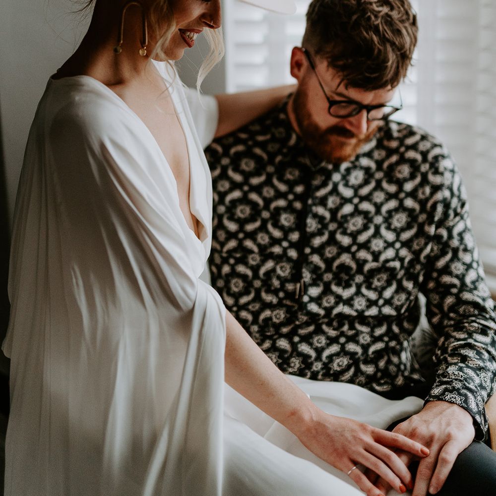 Bride & groom sit with one another at their home on the morning of their wedding day