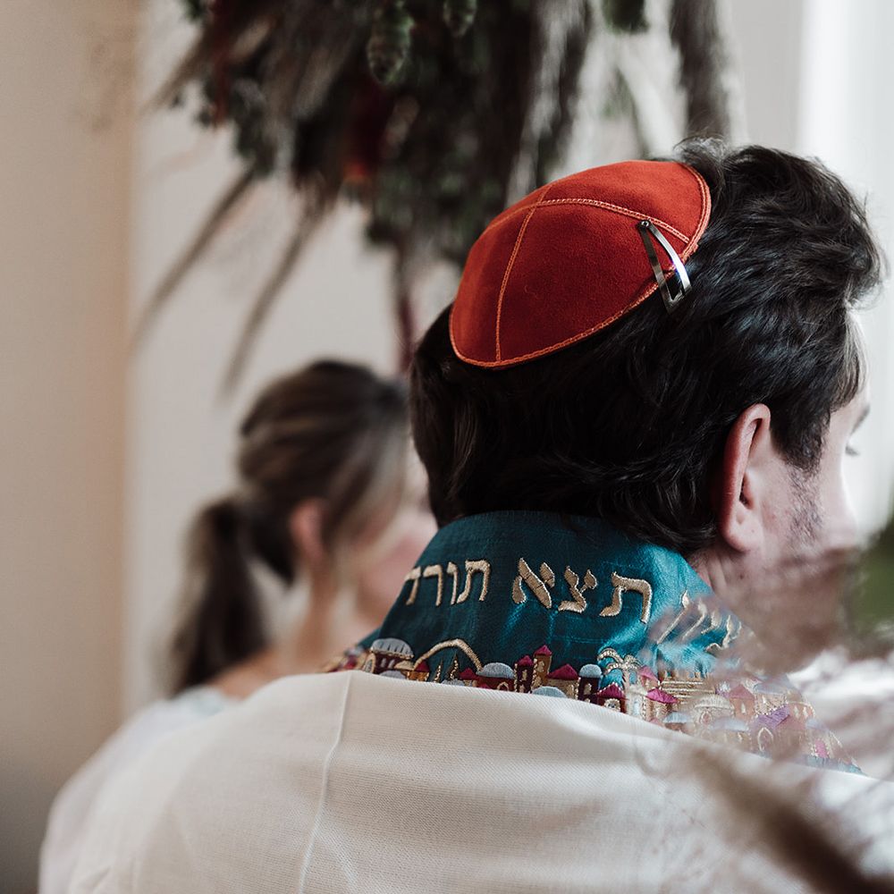 Groom in traditional Jewish wedding attire with red kippah during interfaith wedding ceremony at Iscoyd Park