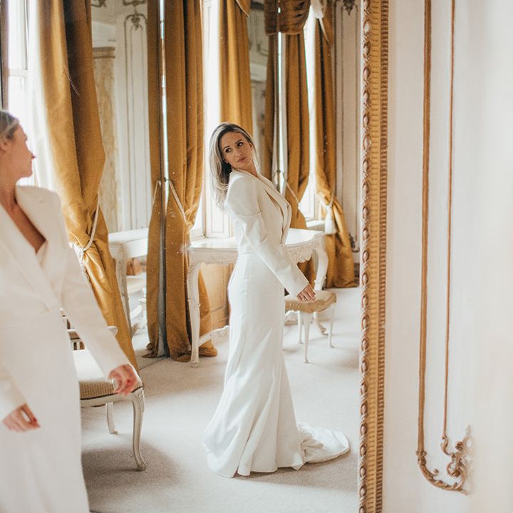 Bride looks at herself in the mirror wearing Zara jacket and sweetheart neckline wedding gown