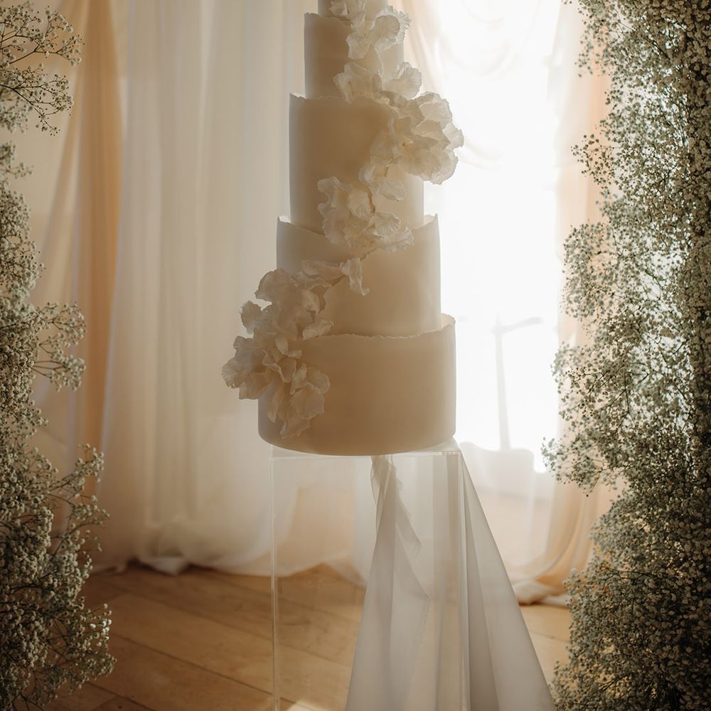 Tall five tier white wedding cake with cascading flower detail