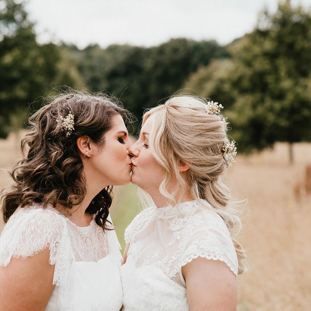 Brides in sheer high neck white wedding dresses share a kiss