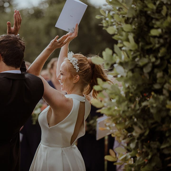 Bride and groom raise their hands in celebration as they sing 
