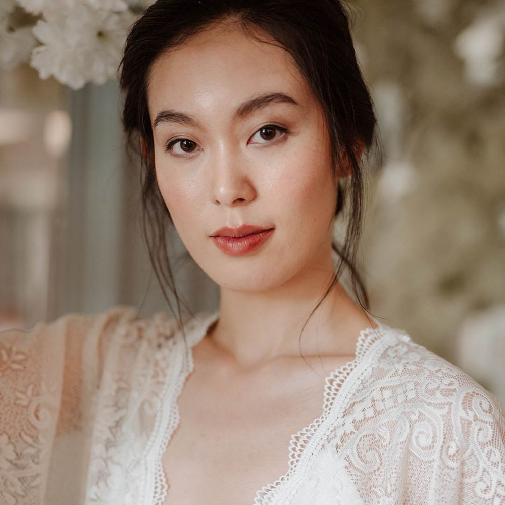 East Asian bride in a lace kimono style wedding dress with natural eyeshadow makeup and subtle red lipstick