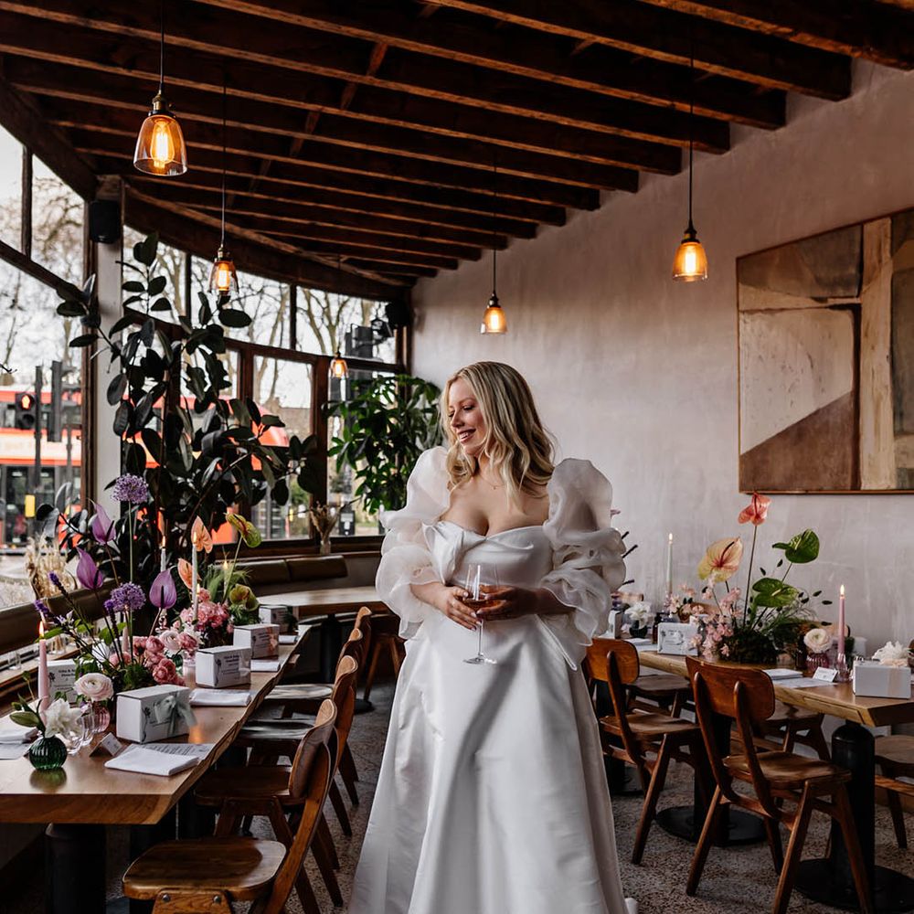 Florist bride in a Jesus Peiro wedding dress with sheer long voluminous sleeves standing in her wedding reception 