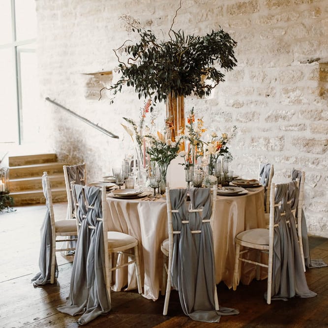wedding reception table and chair back decor with drapes, flower centrepieces and taper candles 