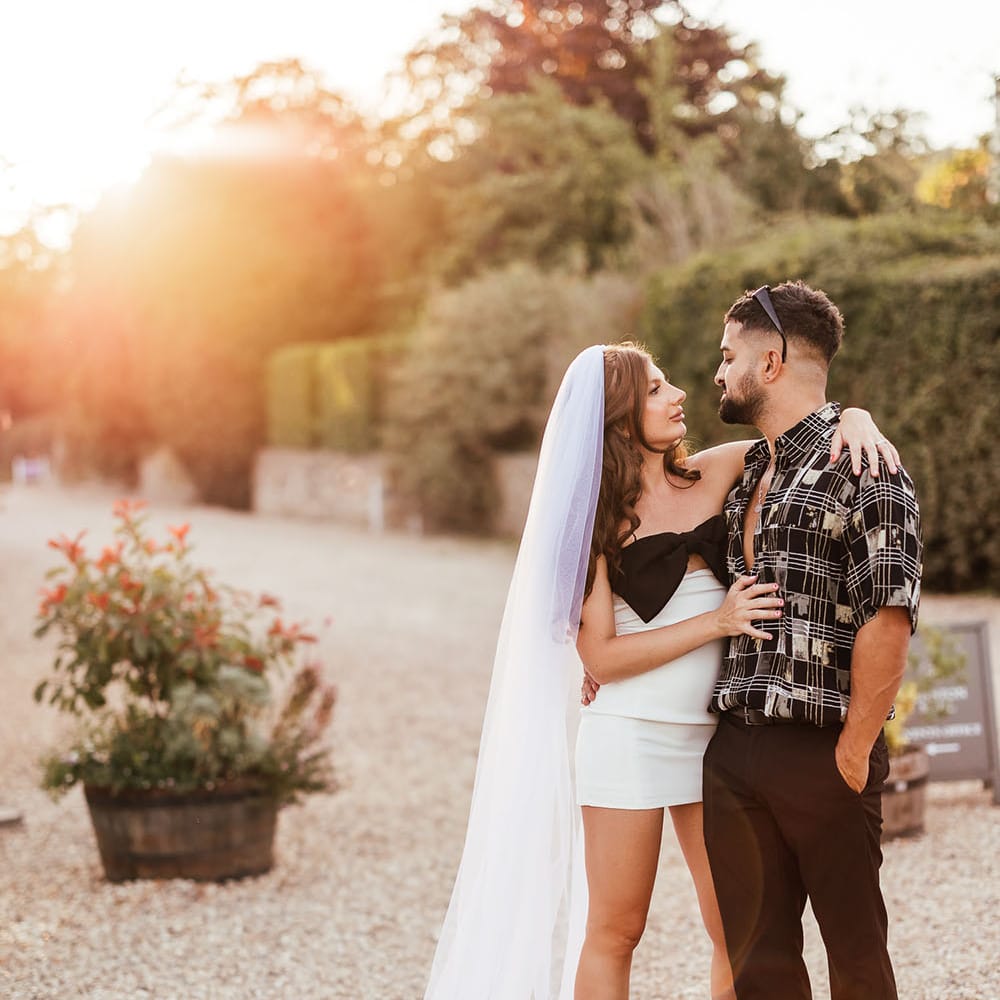 Bride wearing short wedding dress and black strappy heels looks at her who groom during golden hour portraits outdoors 